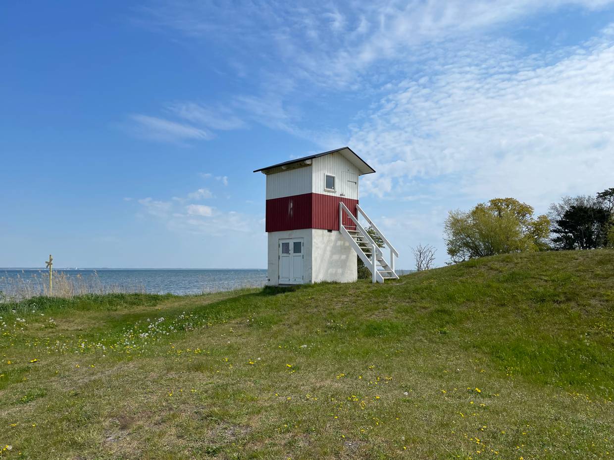 Rot-weißer Holztturm auf einer Wiese am Meer