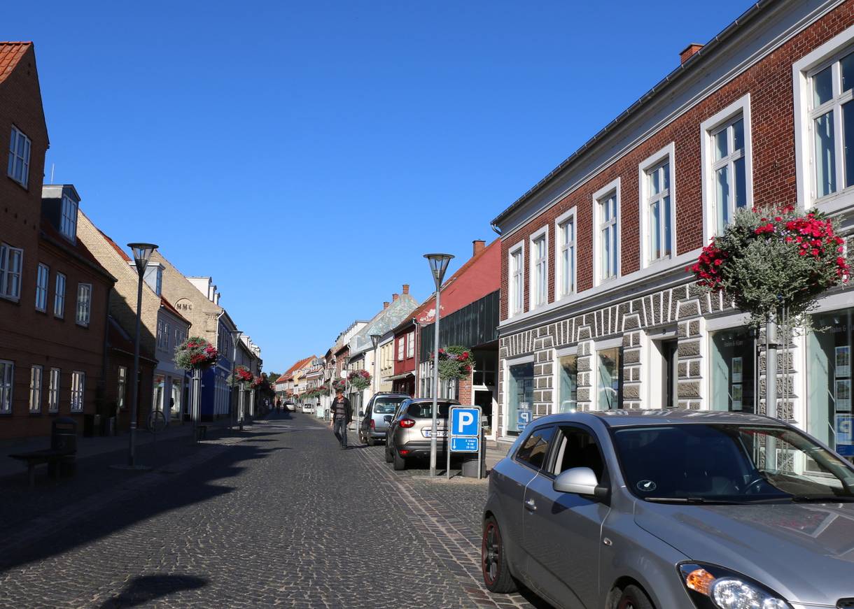 Blick auf eine Straße mit gepflegten alten Häusern und einigen Autos am Straßenrand