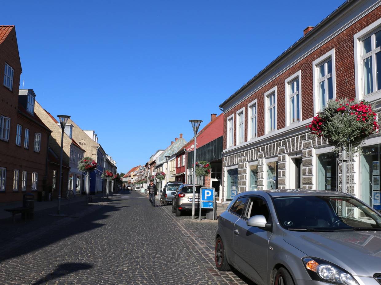 Blick auf eine Straße mit gepflegten alten Häusern und einigen Autos am Straßenrand