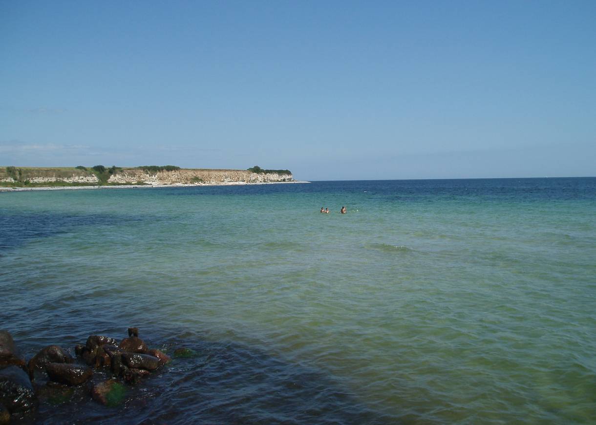 Badegäste in einer türkisen Bucht vor einer Steilküste