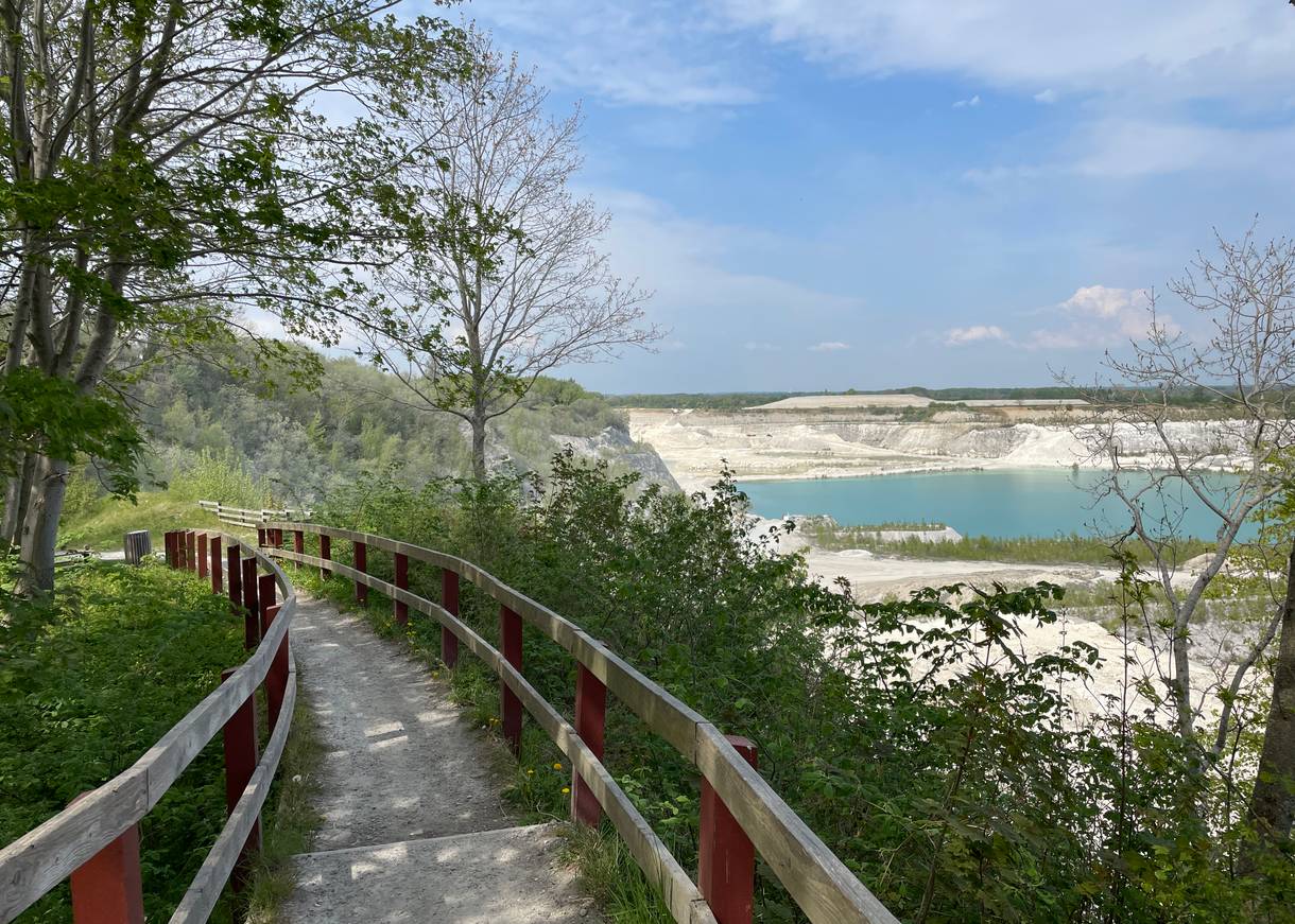 Holzsteg am Hang über einem blauen See im Kalkbruch
