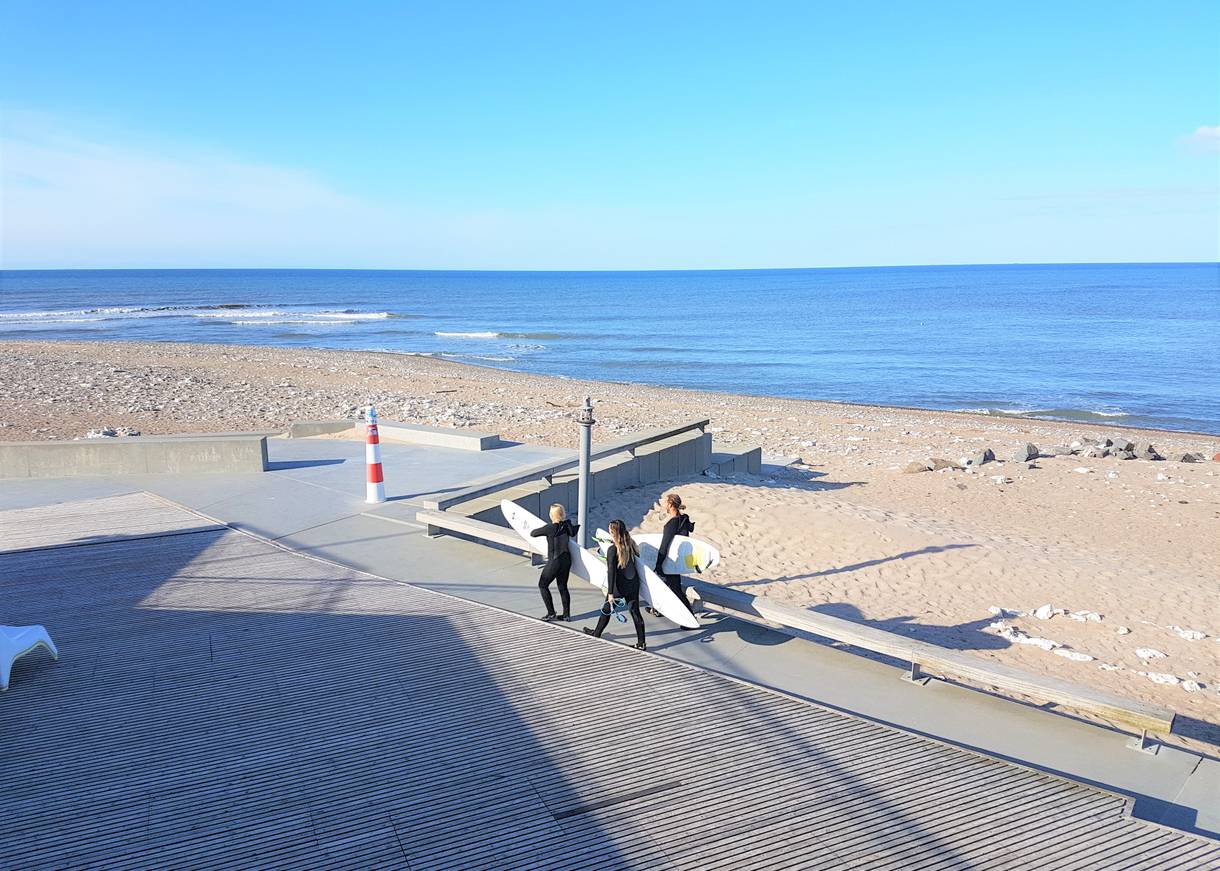 Surfer mit Boards unter dem Arm auf dem Weg zum Wasser