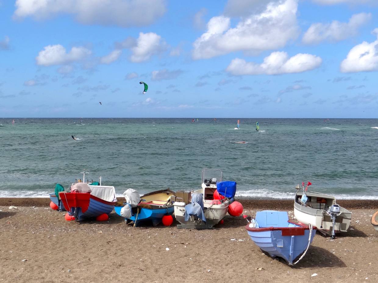 Surfer auf der Nordsee, davor kleine Boote auf dem Strand