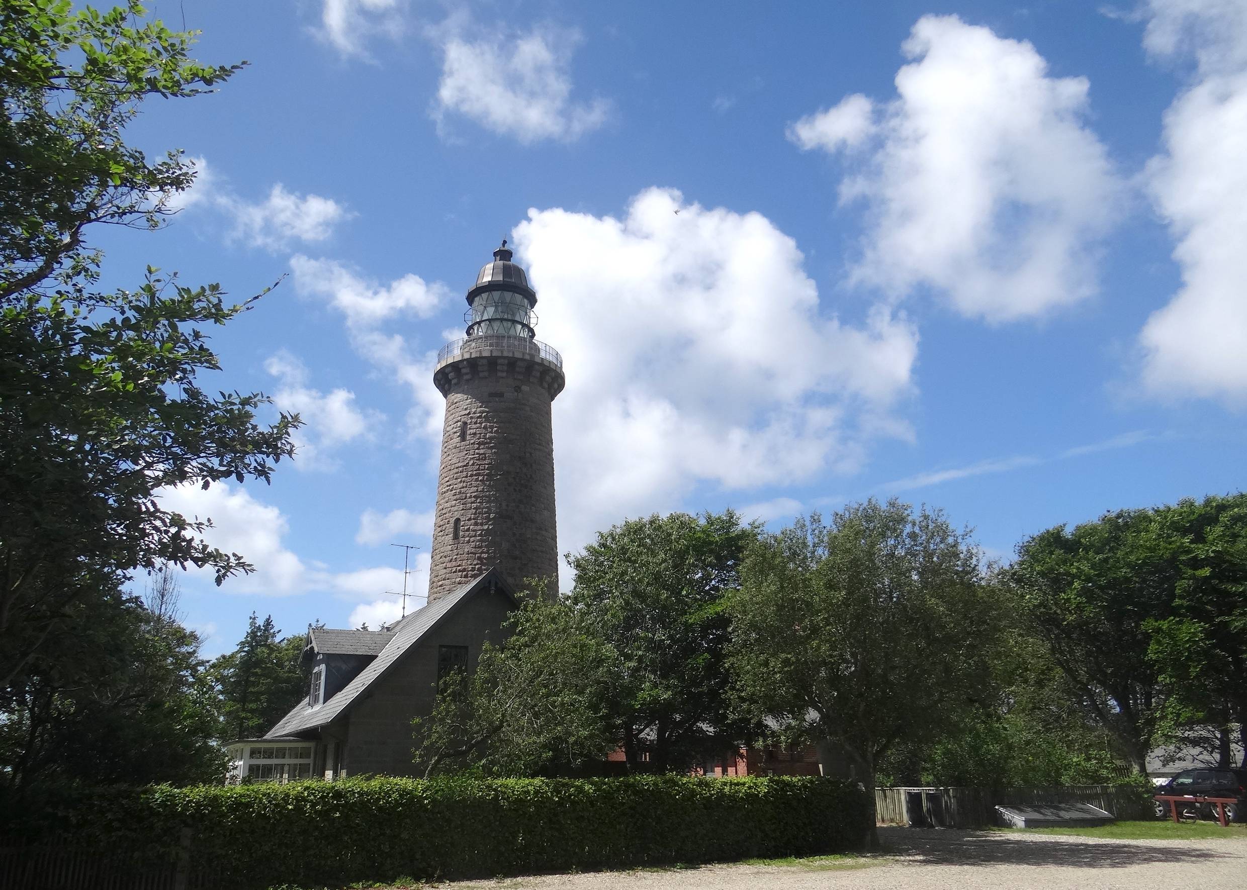 Ein Leuchtturm aus grauem Granitstein im Wald
