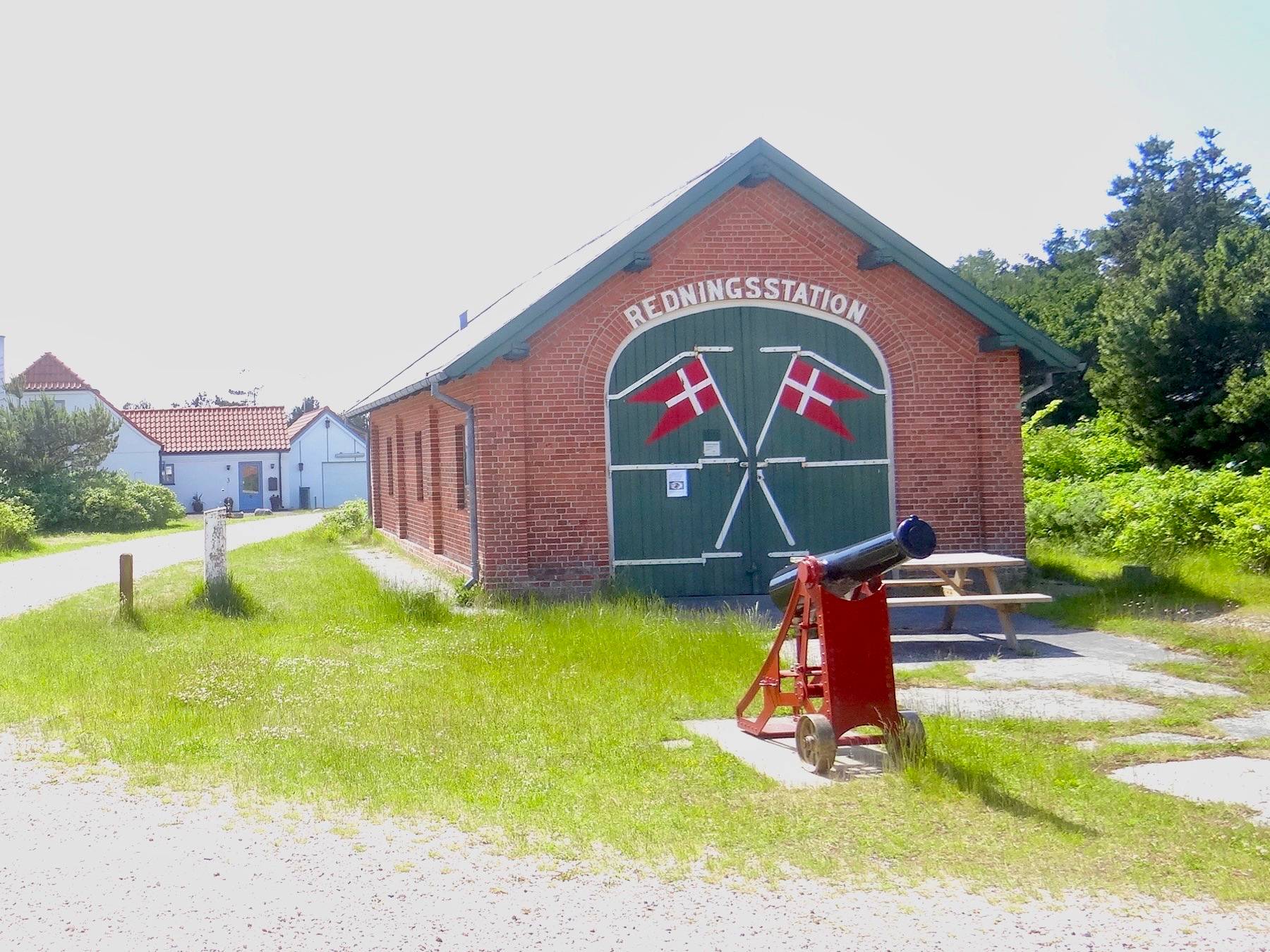Traditionelles Rettungshaus mit grünen Tor, auf das zwei sich kreuzende Flaggen gemalt sind