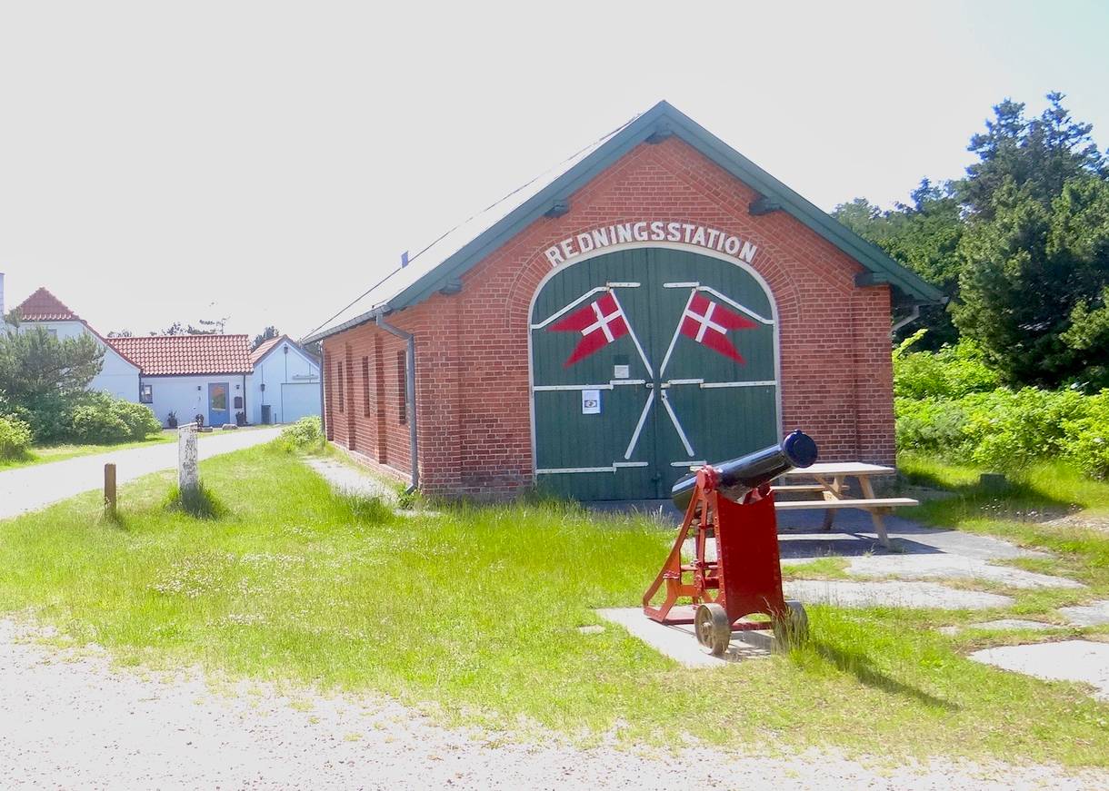 Traditionelles Rettungshaus mit grünen Tor, auf das zwei sich kreuzende Flaggen gemalt sind