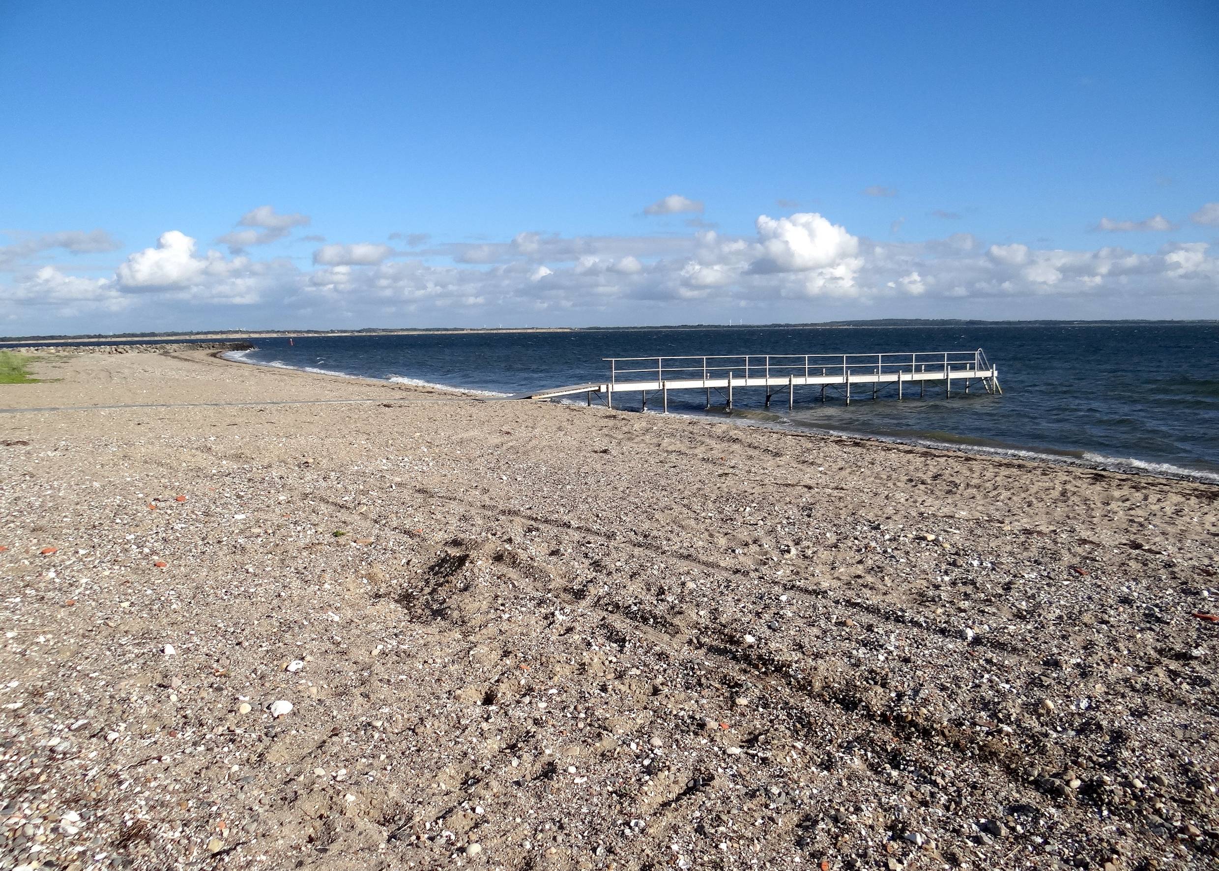 Badesteg vor einem steinigen Sandstrand