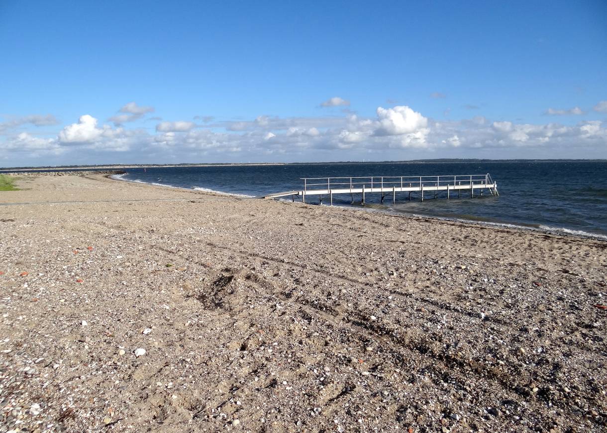 Badesteg vor einem steinigen Sandstrand