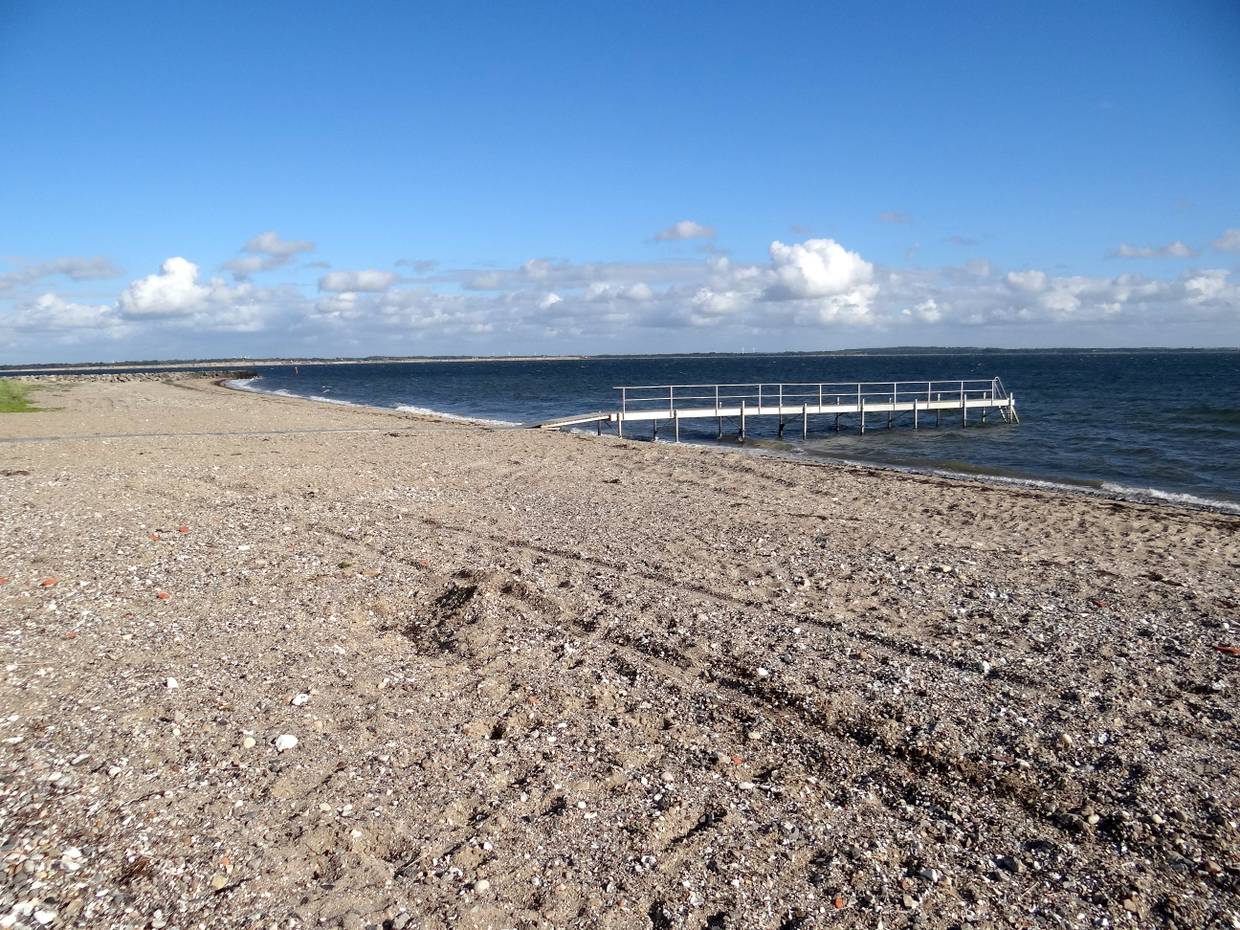 Badesteg vor einem steinigen Sandstrand