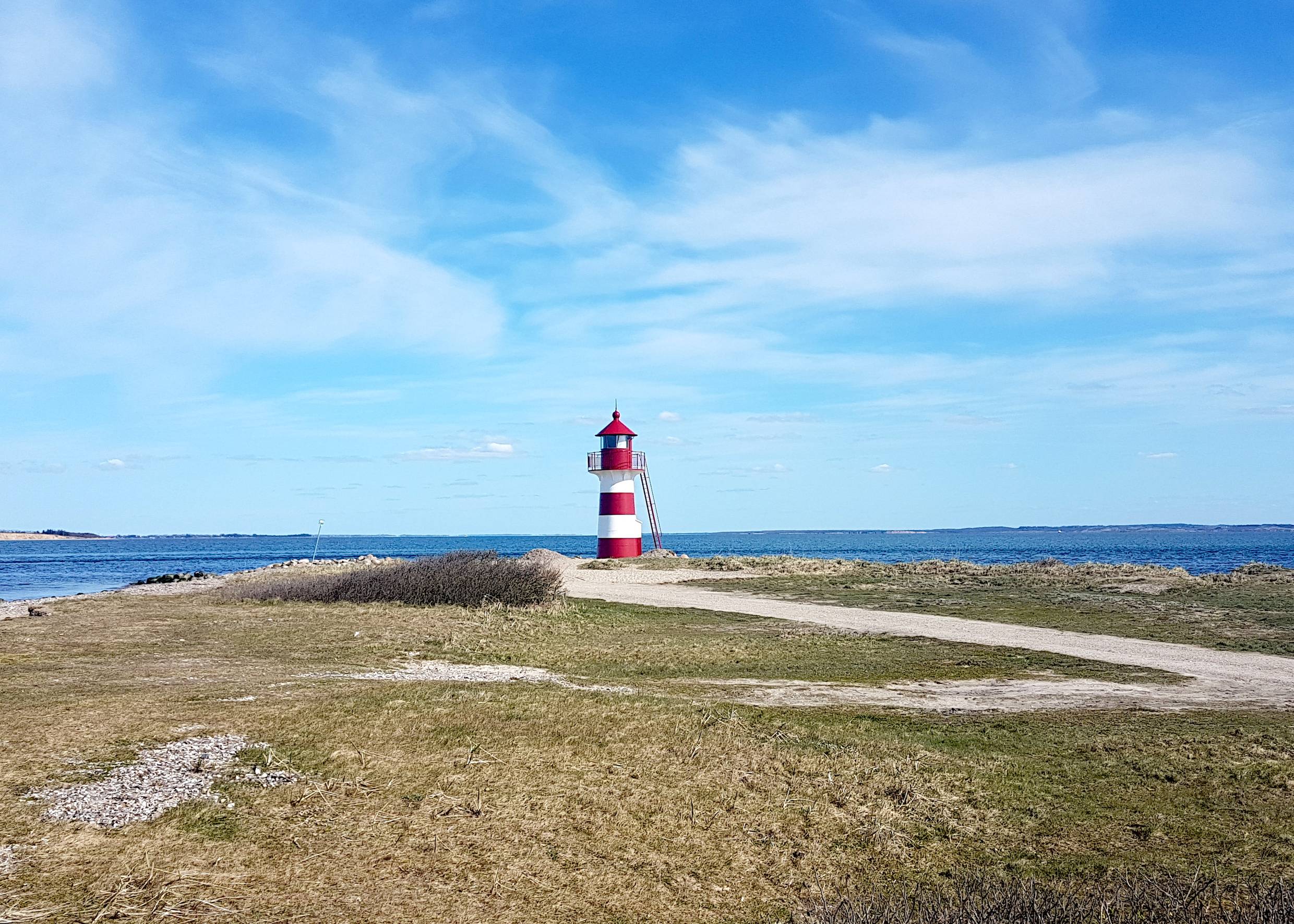 Rot-weißer Leuchtturm vor blauem Himmel