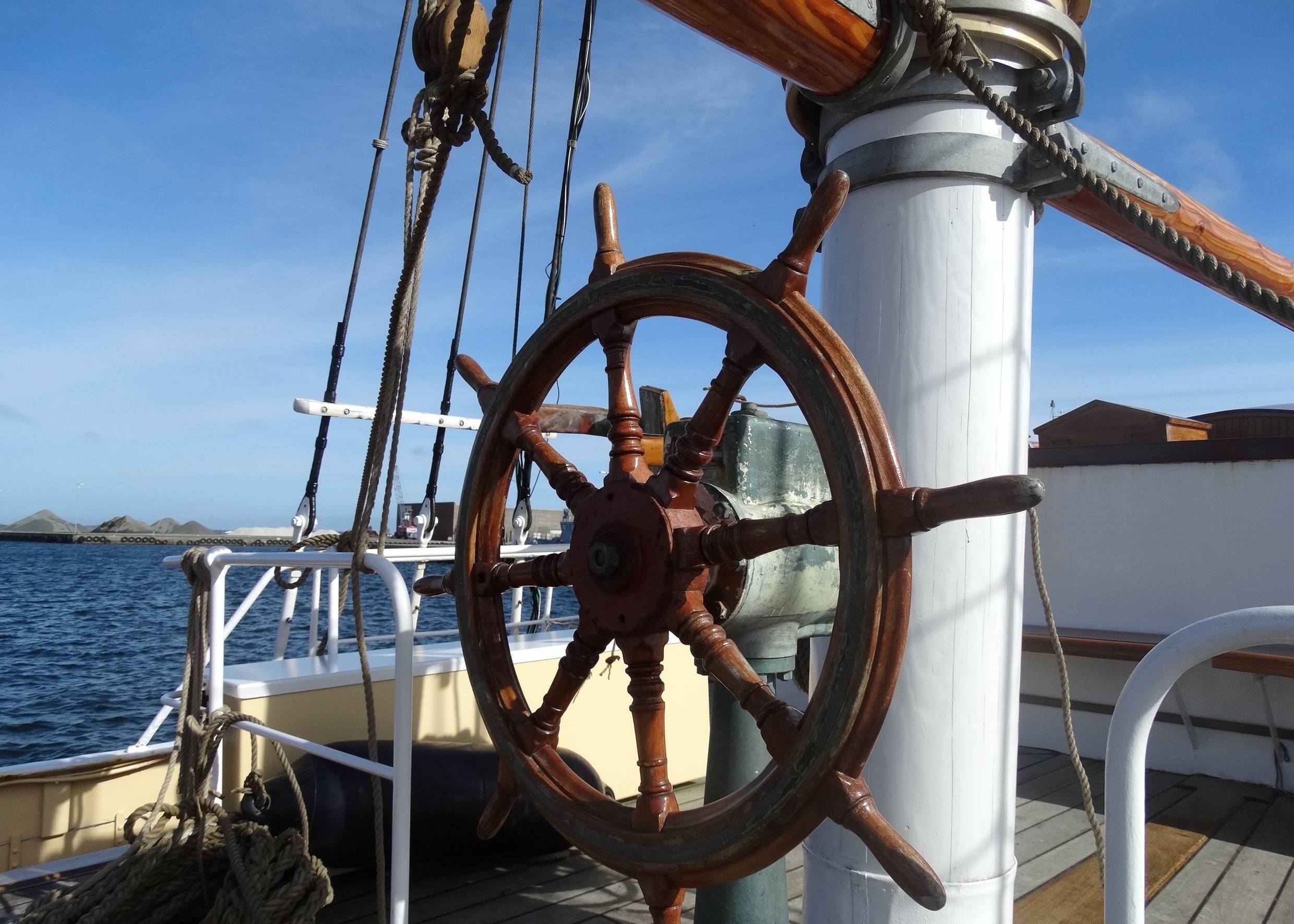Hölzernes Steuerrad auf einem Segelkutter, dahinter der Limfjord