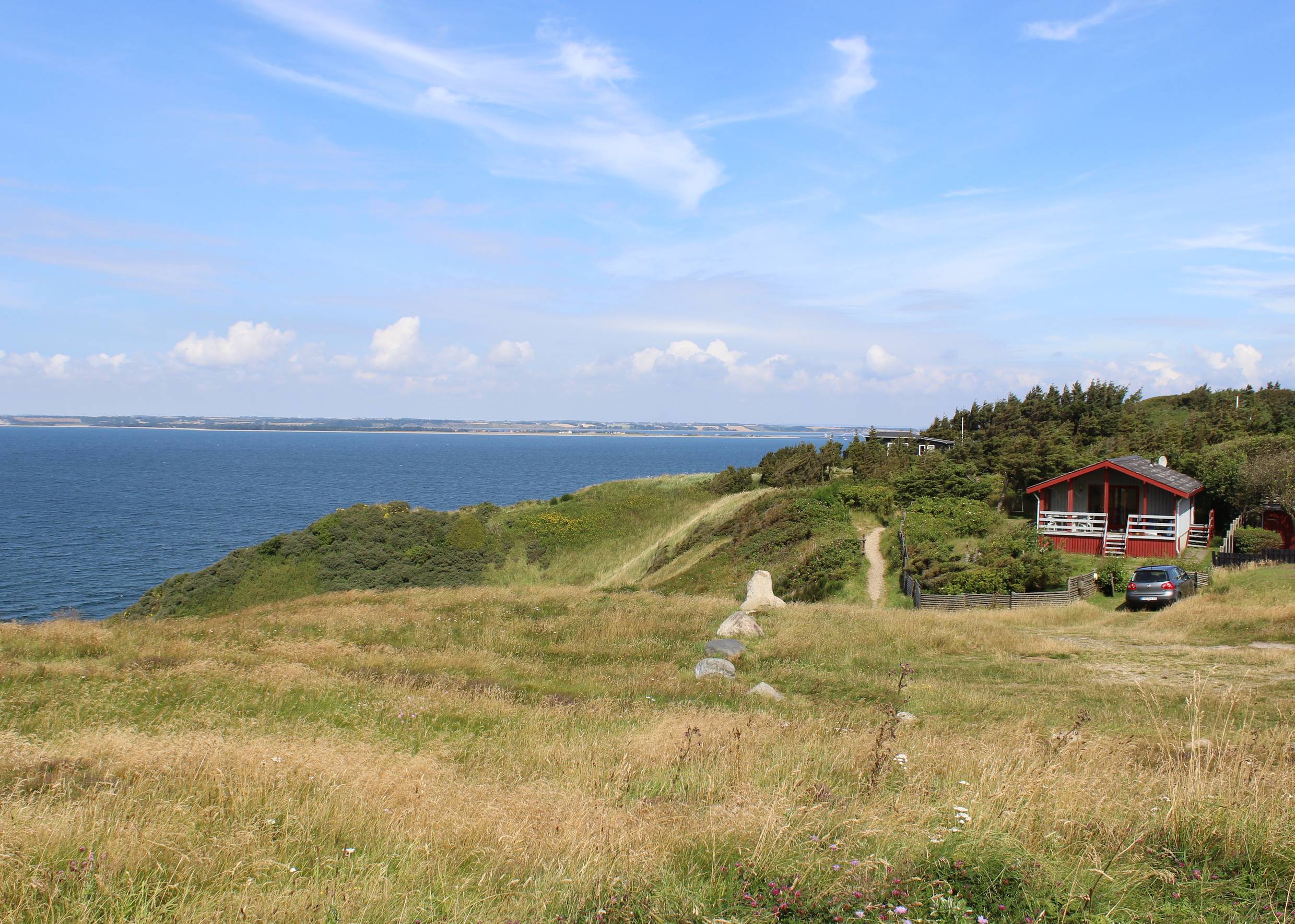Rotes Ferienhaus auf einem grünen Hügel über dem Limfjord
