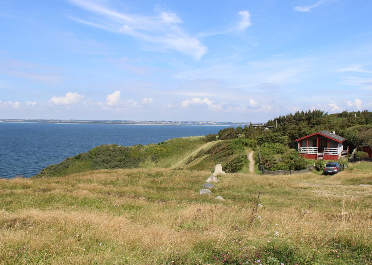 Rotes Ferienhaus auf einem grünen Hügel über dem Limfjord