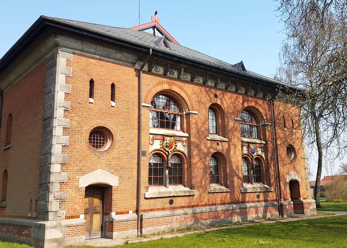 Rechteckiges Backsteinhaus mit Wappendekoration über den großen Fenstern