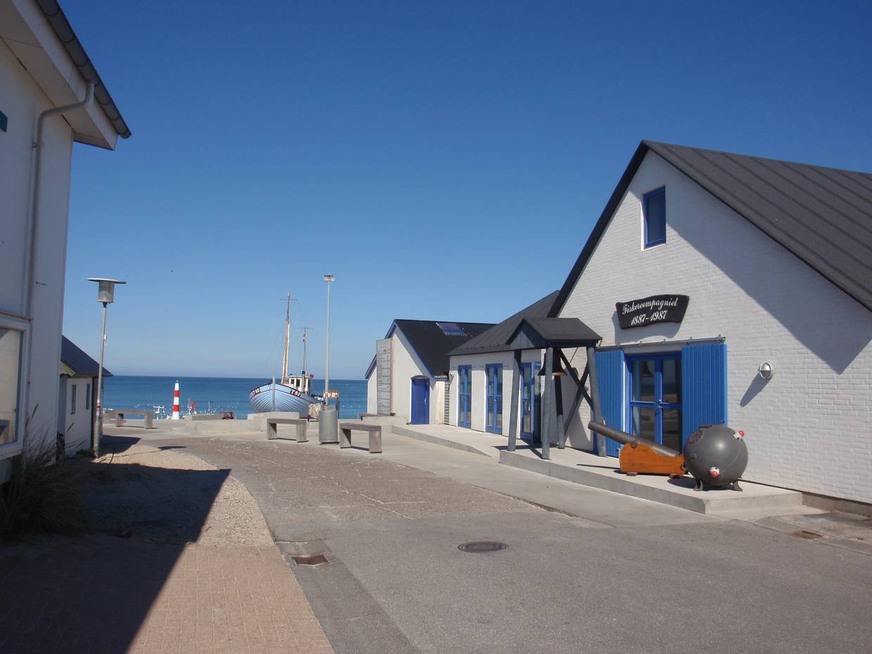 Aussicht zwischen weißen Häusern auf den Strand mit Booten