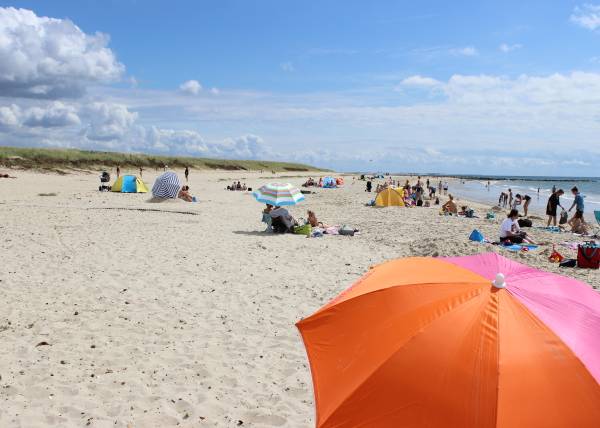Strandbesucher mit vielen Sonnenschirmen