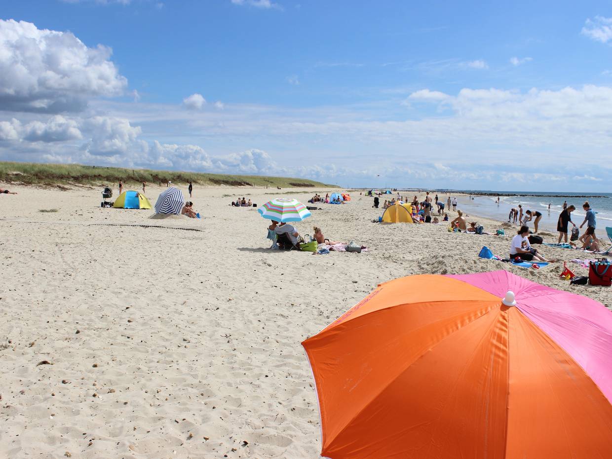 Strandbesucher mit vielen Sonnenschirmen