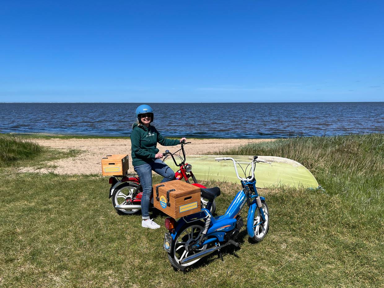 Zwei Mopeds am Fjordstrand, auf einem Sitzt eine Frau mit Helm