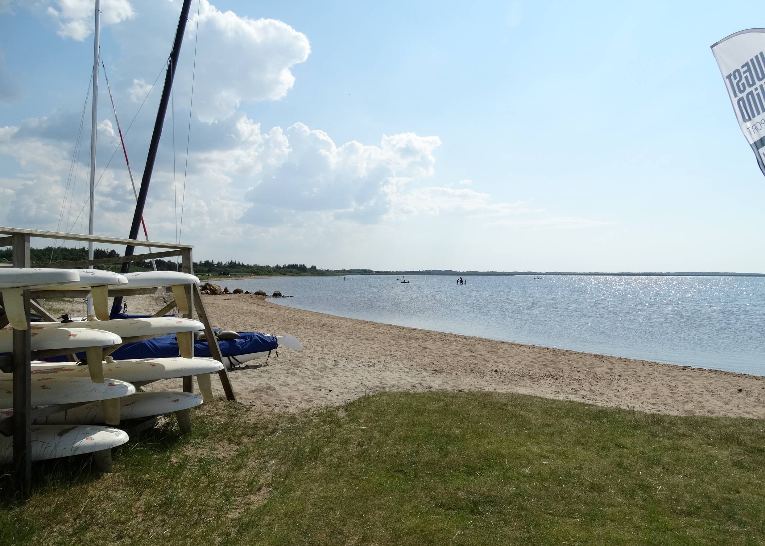 Sandstrand am Fjord mit einem Stapel Surfboards am Ufer