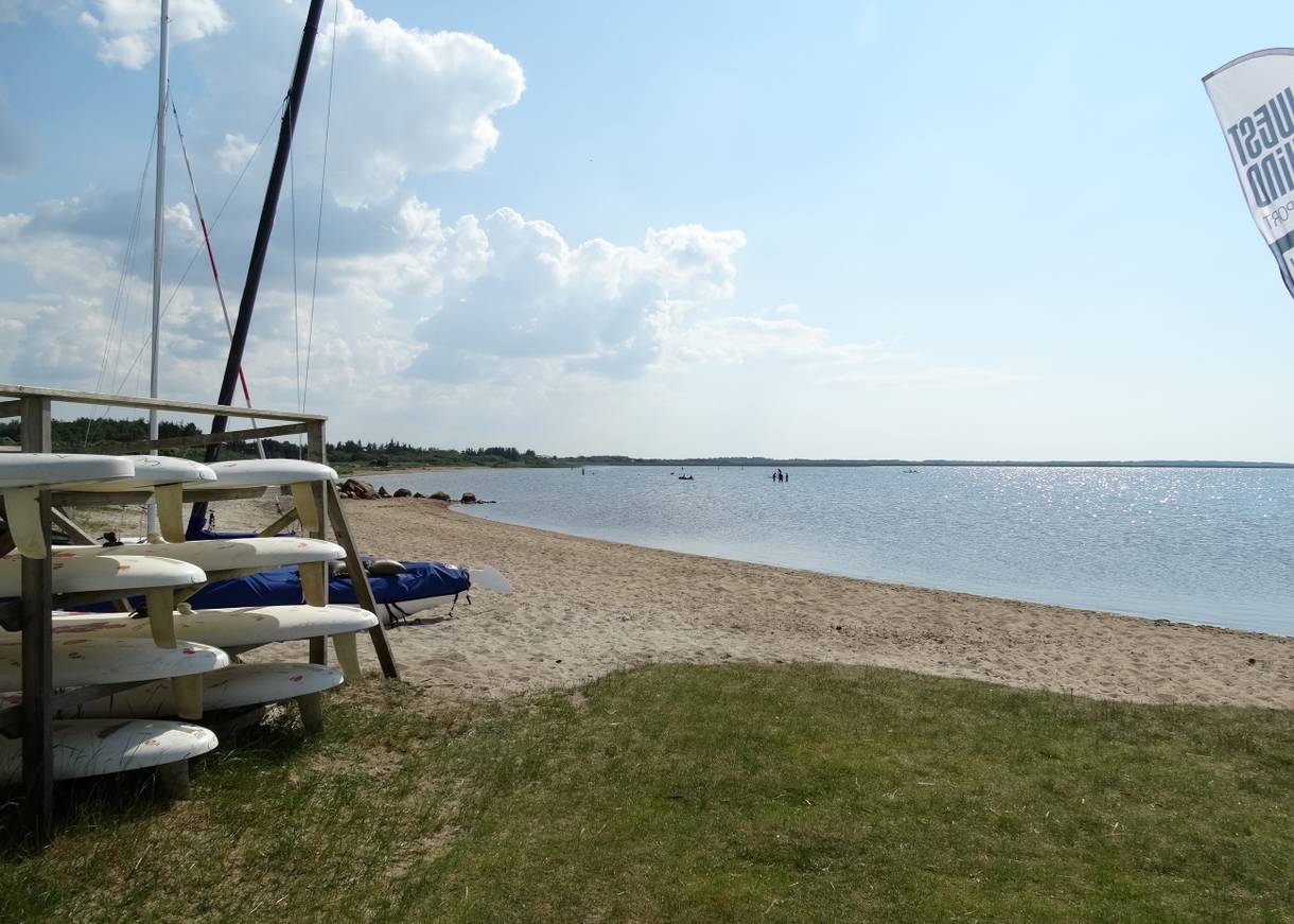 Sandstrand am Fjord mit einem Stapel Surfboards am Ufer