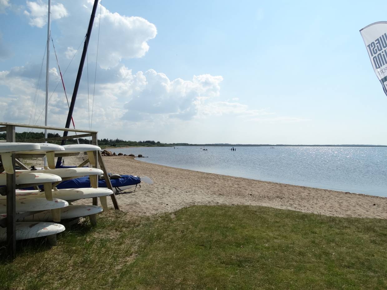 Sandstrand am Fjord mit einem Stapel Surfboards am Ufer