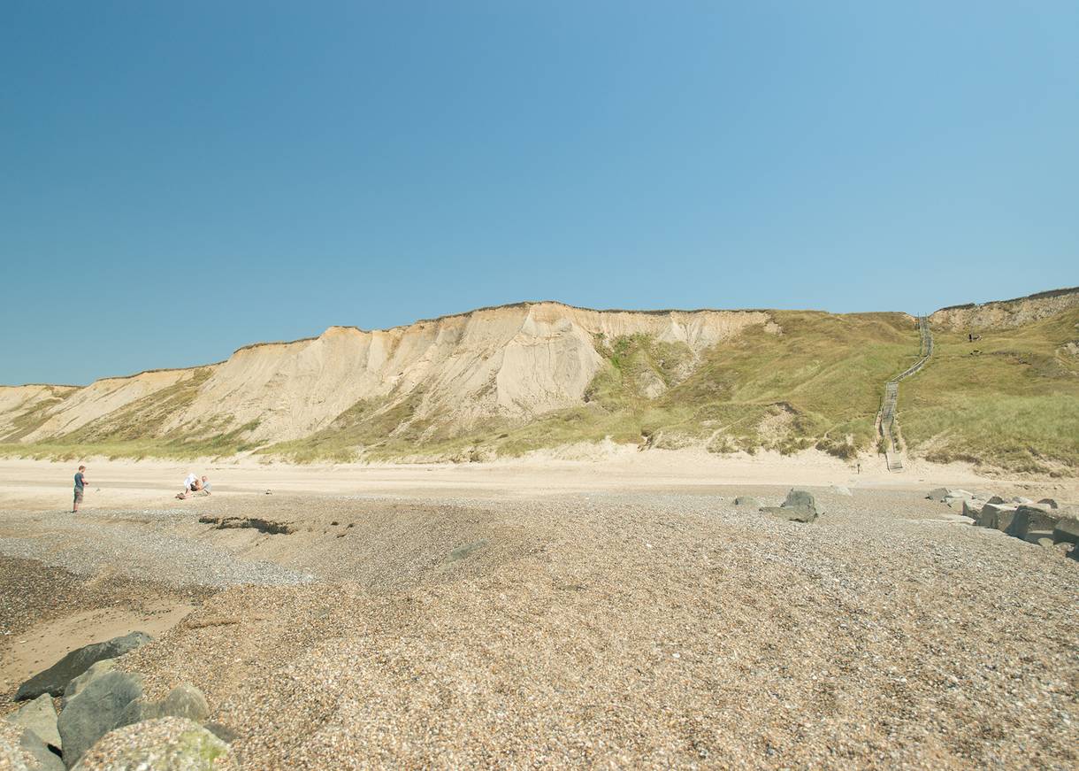 Steiniger Strand, dahinter erhebt sich eine Steilküste