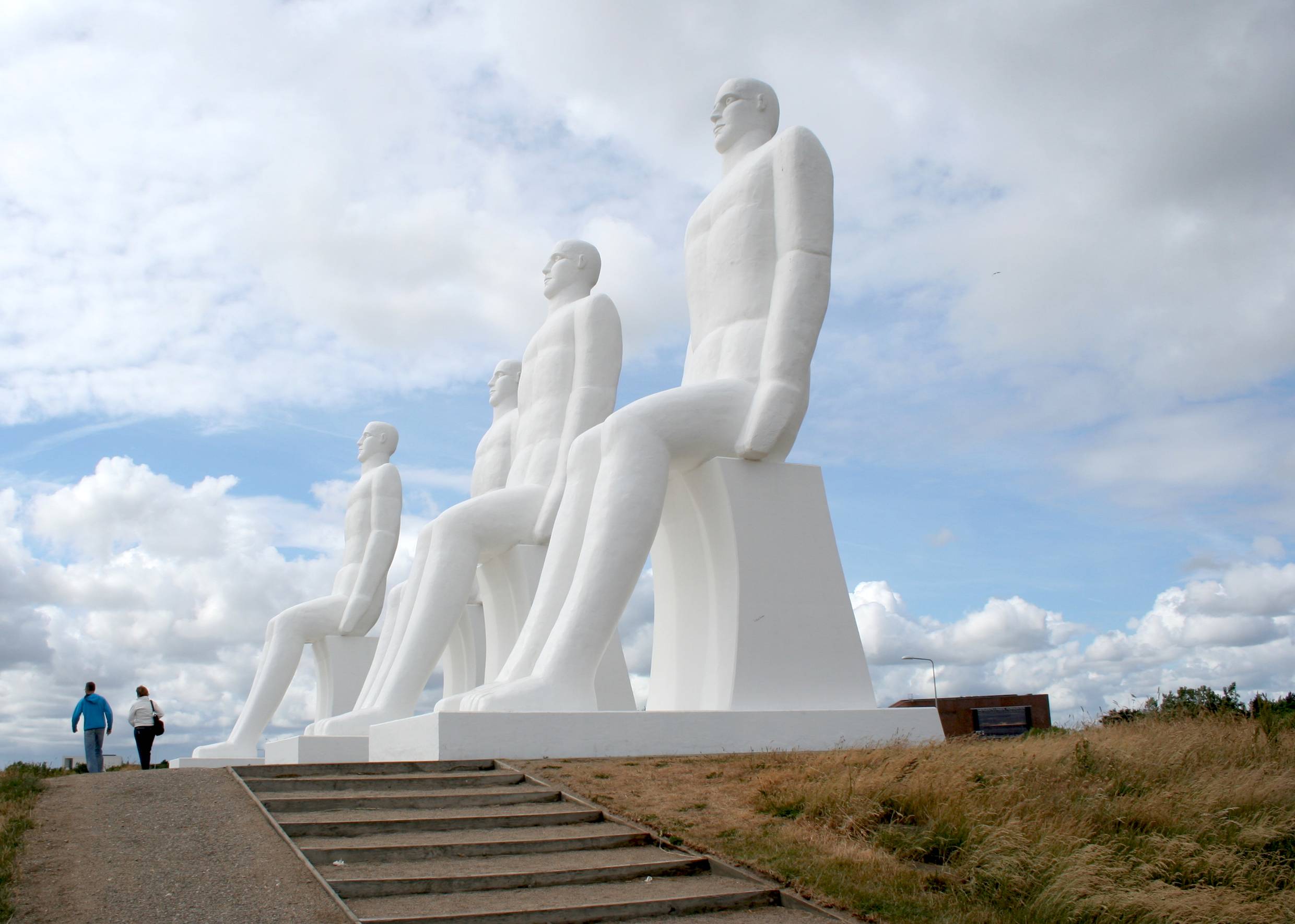 Weiße, überlebensgroße Skulptur mit vier sitzenden Menschen am Strand