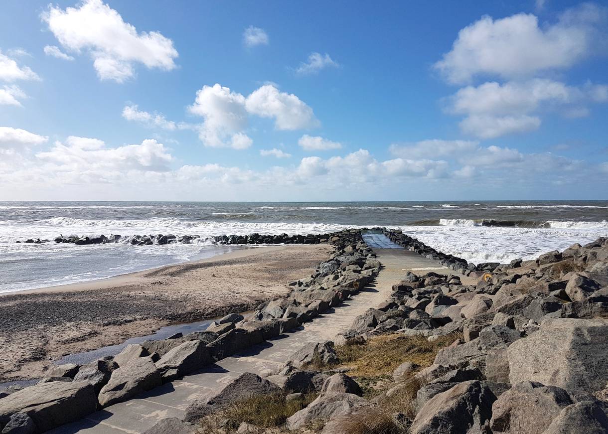 Plattenweg auf einer Granitbune zum Wasser