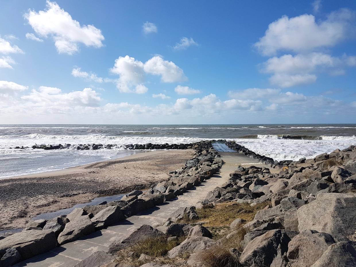 Plattenweg auf einer Granitbune zum Wasser