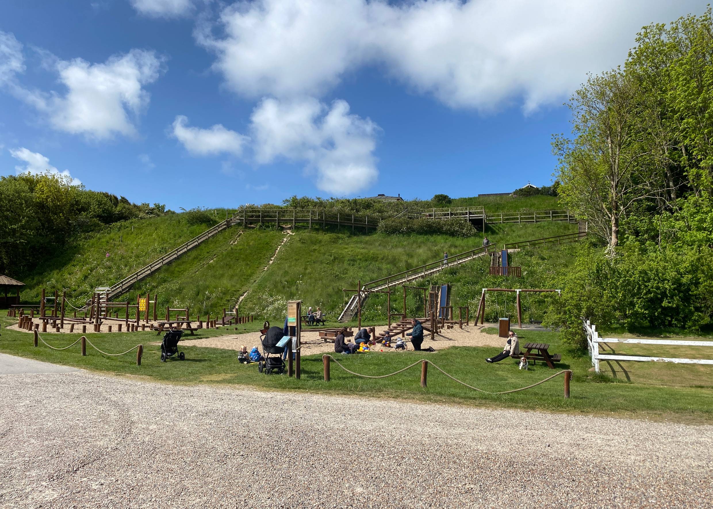 Spielplatz vor einem grünen Hügel bei Sommerwetter