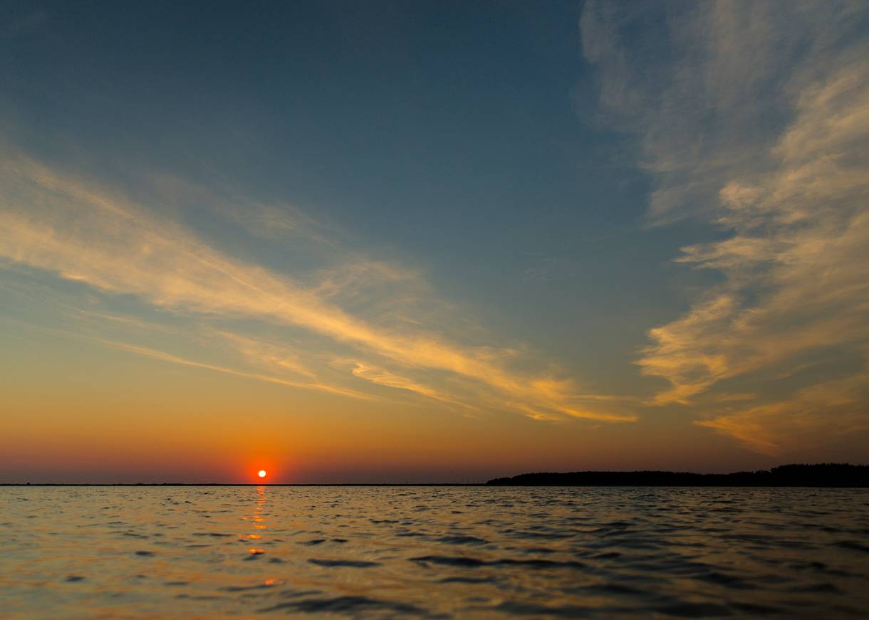 Sonnenuntergang über einem windstillen Gewässer