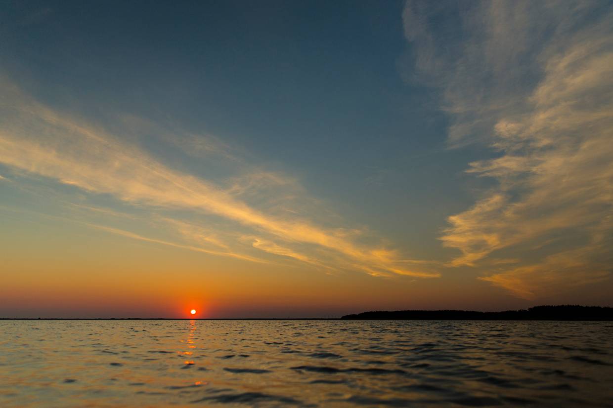 Sonnenuntergang über einem windstillen Gewässer