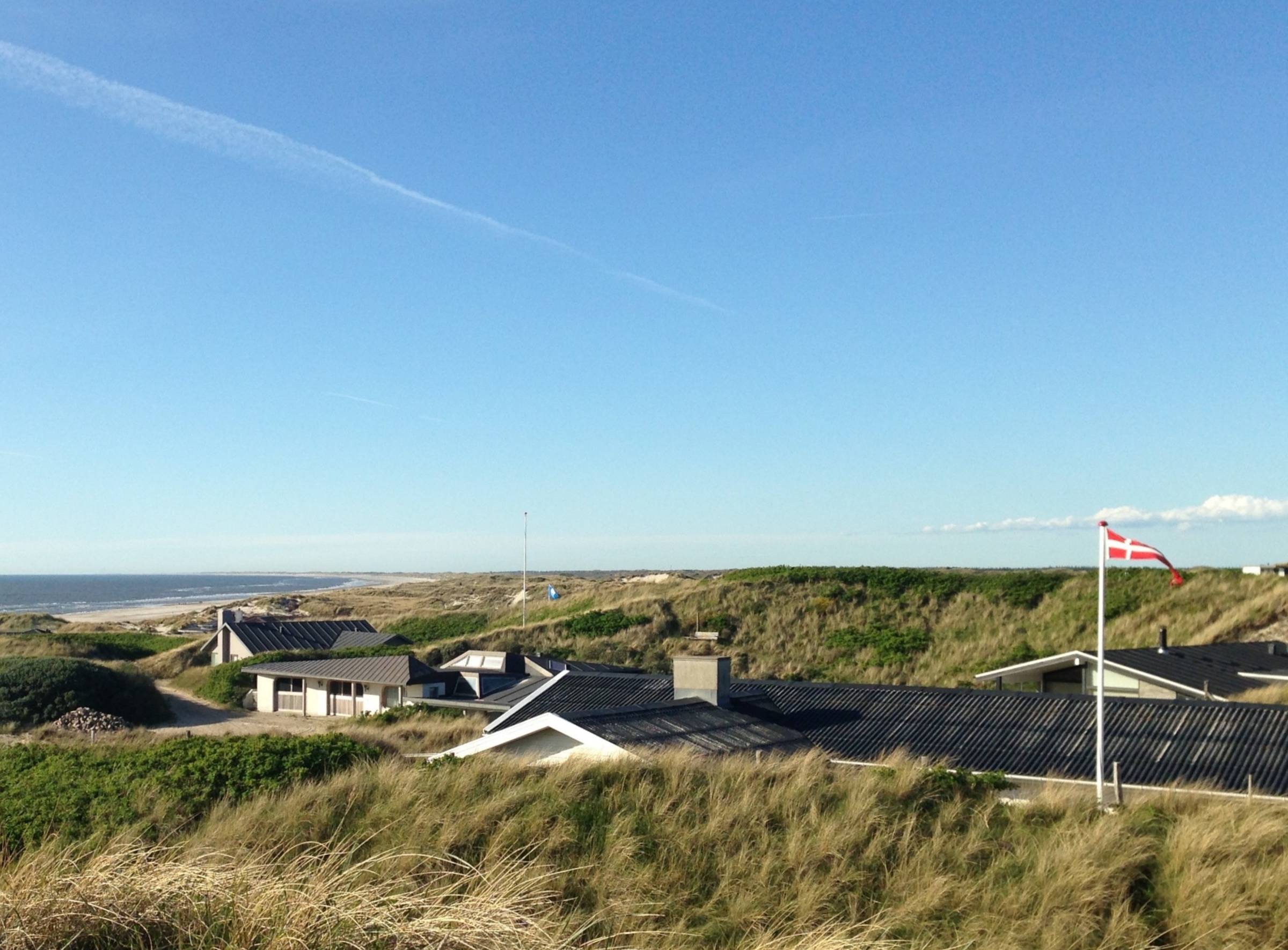 Blick von einer Düne auf Ferienhäuser und Strand