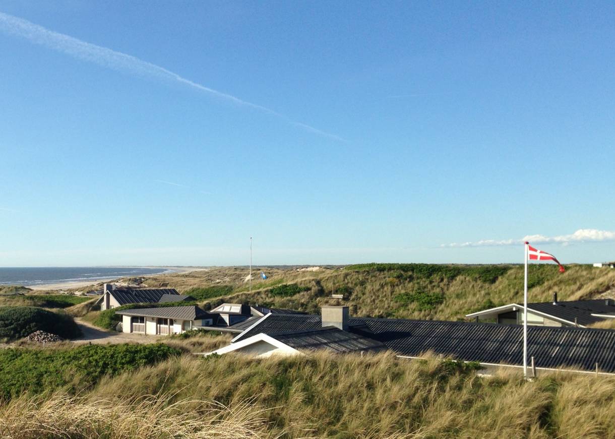 Blick von einer Düne auf Ferienhäuser und Strand