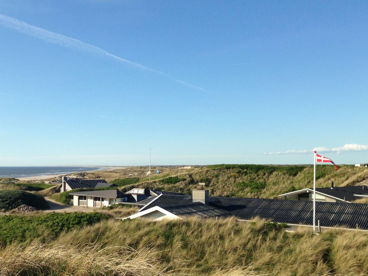 Blick von einer Düne auf Ferienhäuser und Strand