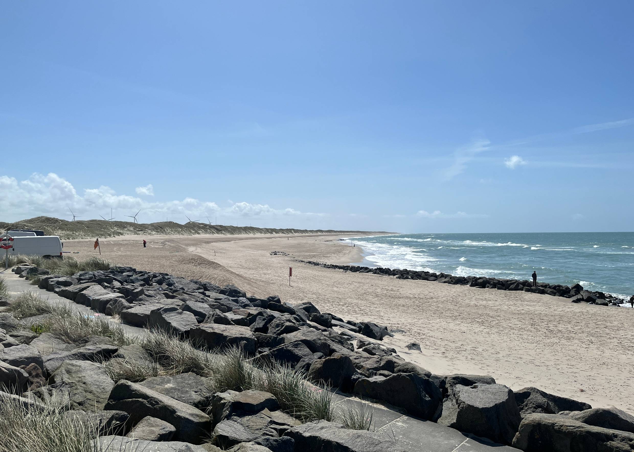 Lange Bucht vor unbebauten Buhnen, steiniger Strand mit Wellen