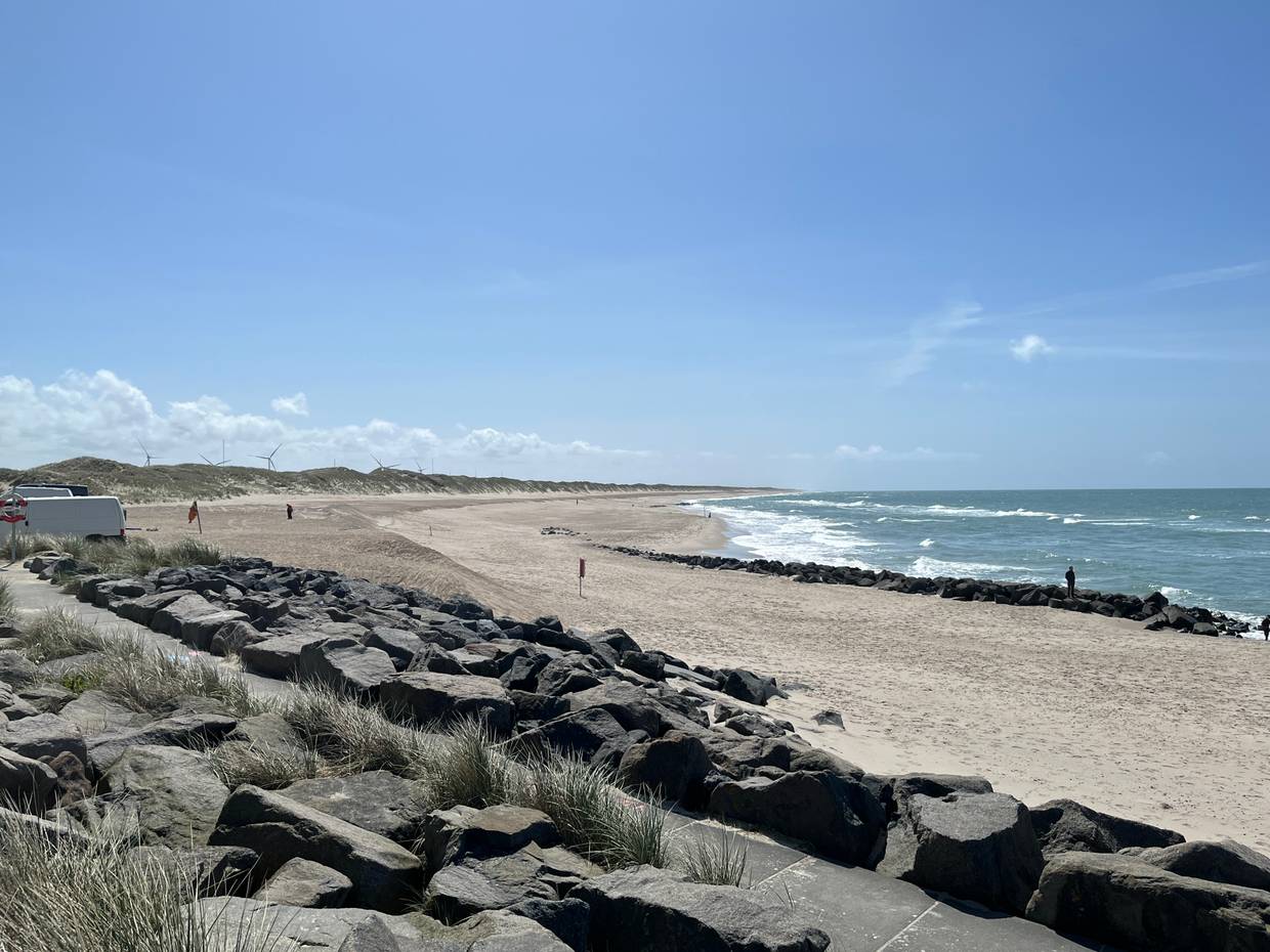 Lange Bucht vor unbebauten Buhnen, steiniger Strand mit Wellen