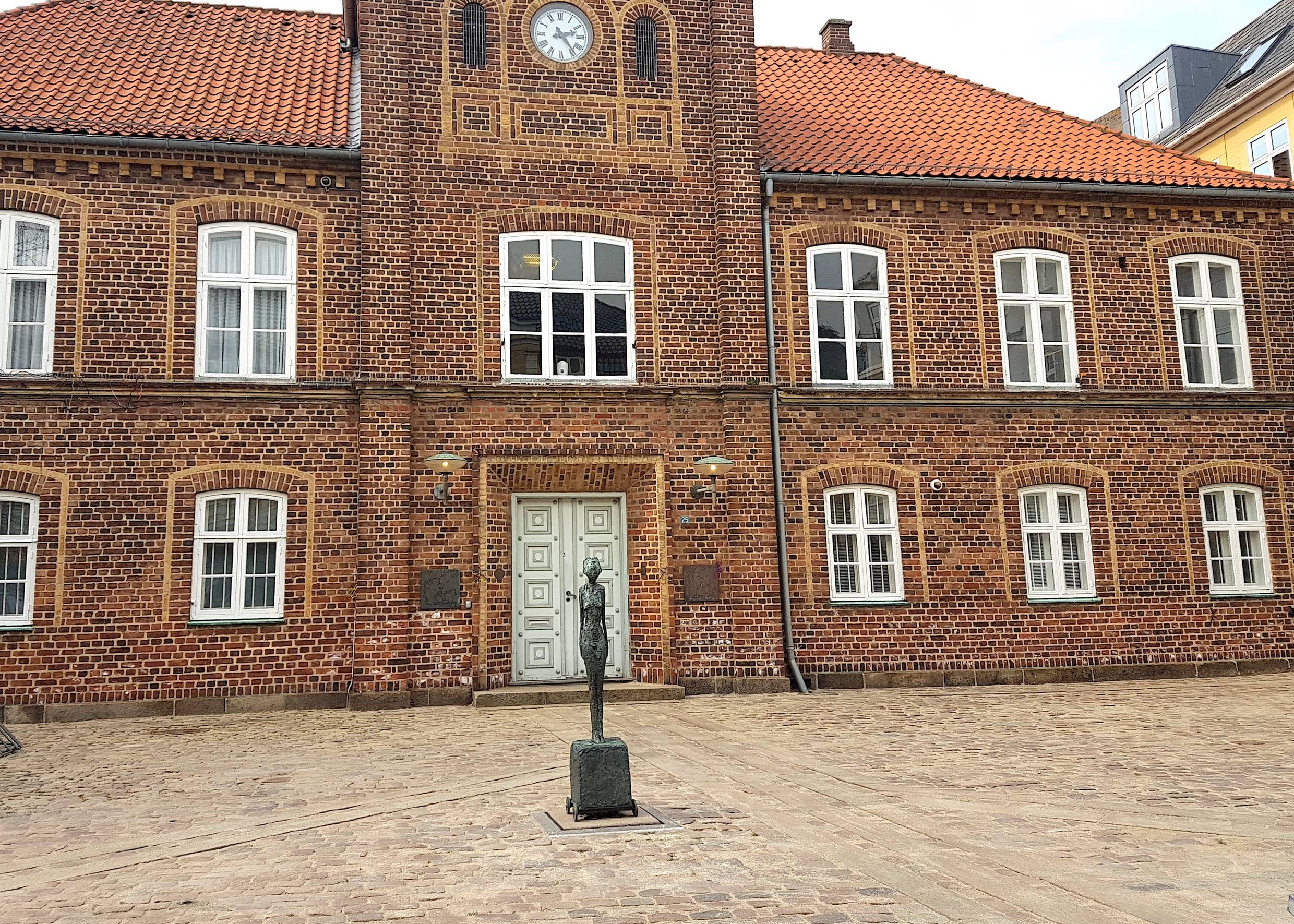 Schmal kleine Figur vor einem Backsteingebäude