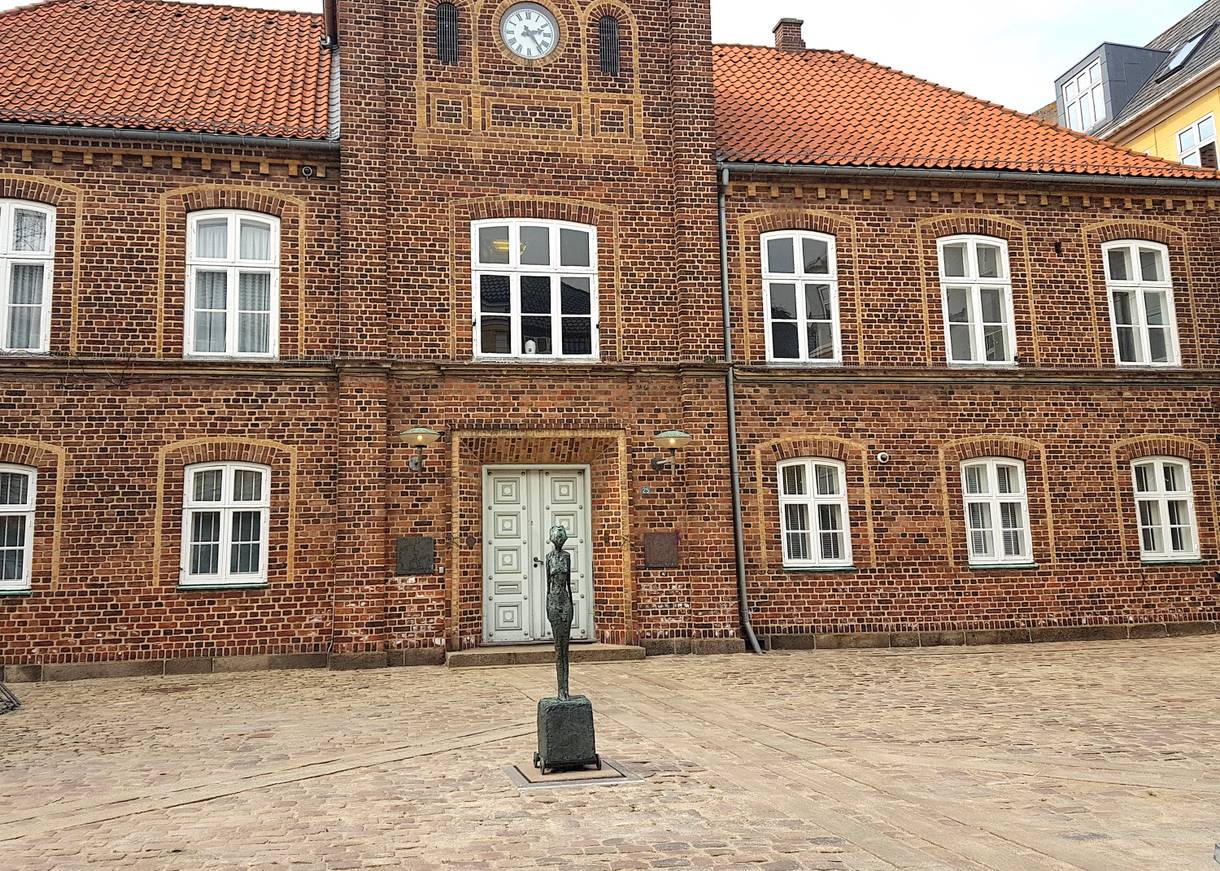Schmal kleine Figur vor einem Backsteingebäude