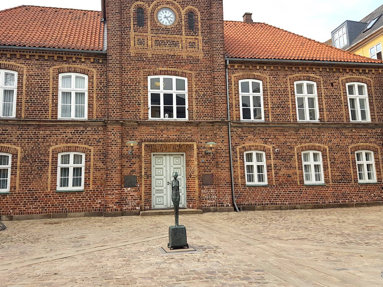 Schmal kleine Figur vor einem Backsteingebäude