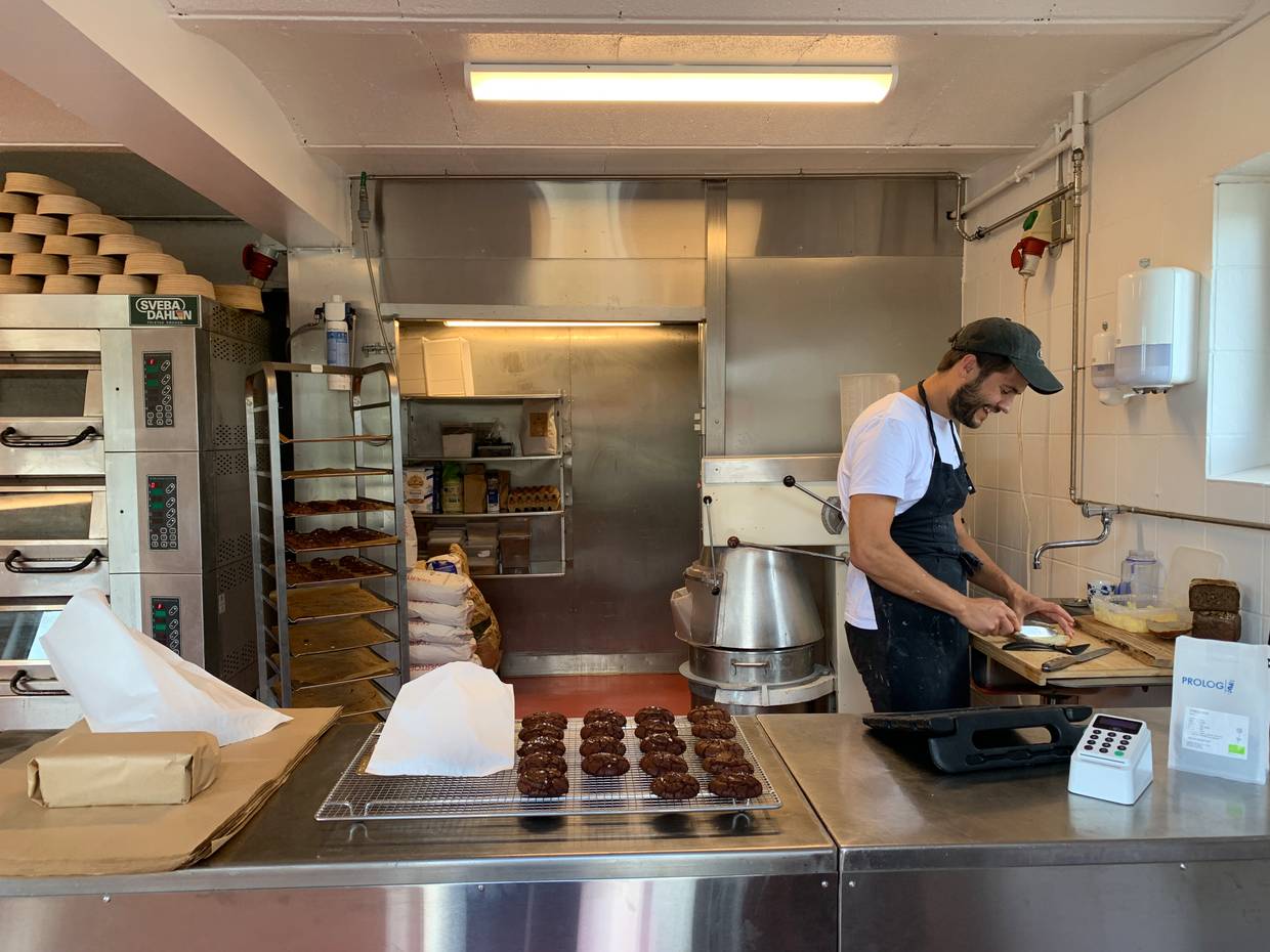 Blick in einer Bäckerei, der Bäcker schmiert ein Brötchen