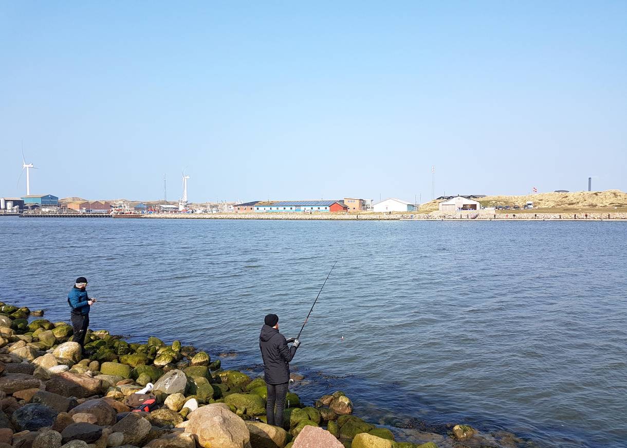 Angler auf der steinigen Mole an der Hafeneinfahrt