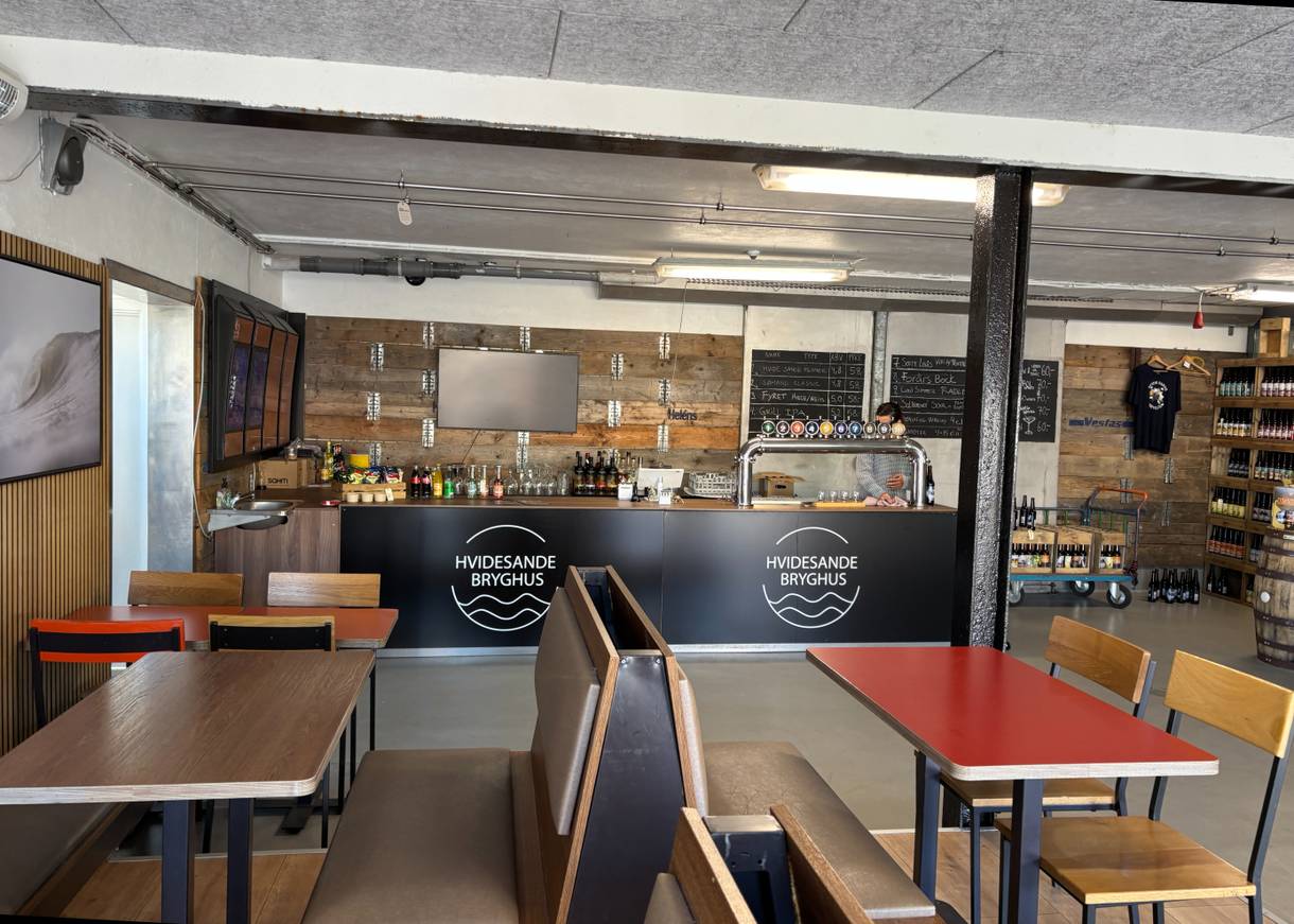 Kleines Lokal eines Brauhauses mit Sitzplätzen, ein Bar mit Zapfanlage und Regale mit Bierflaschen