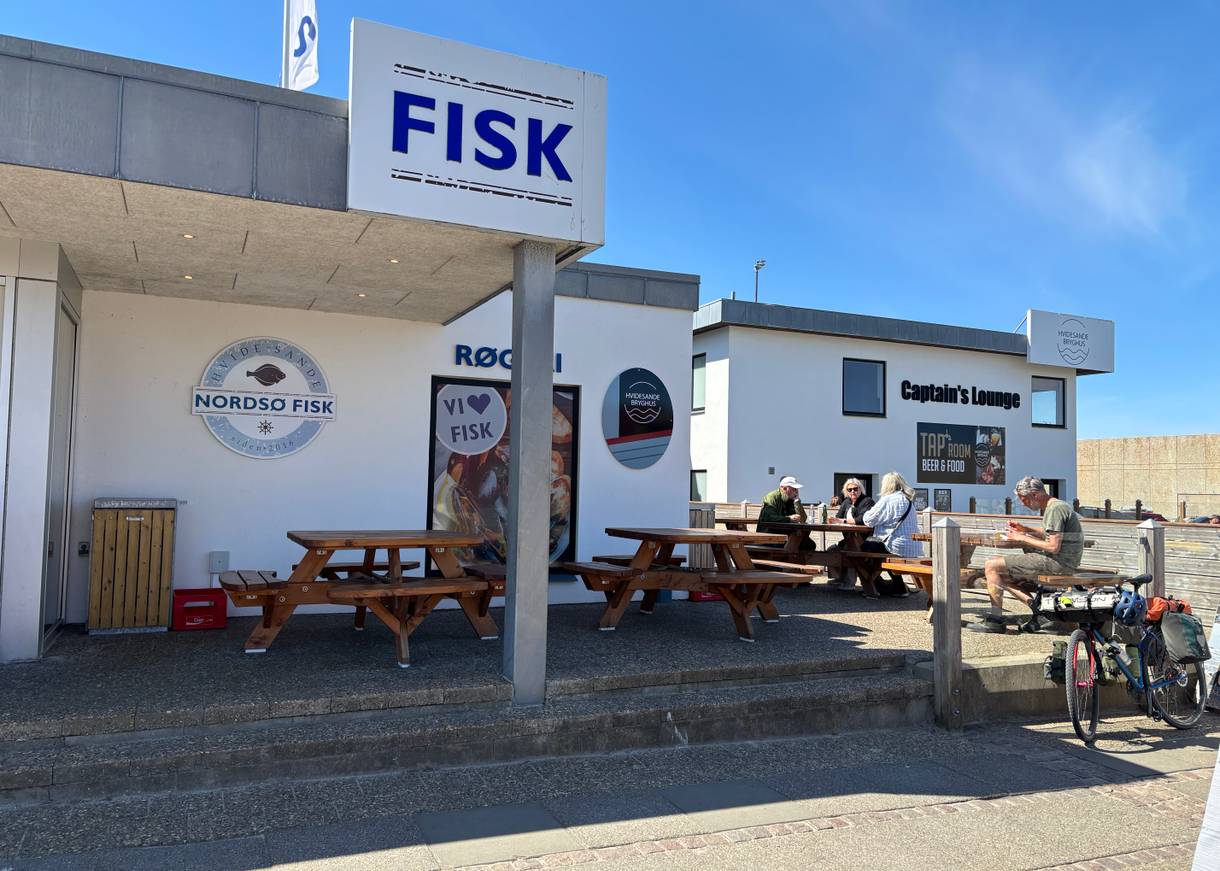 Fischräucherei mit Bänken und Kunden, die sich zum Essen niedergelassen haben