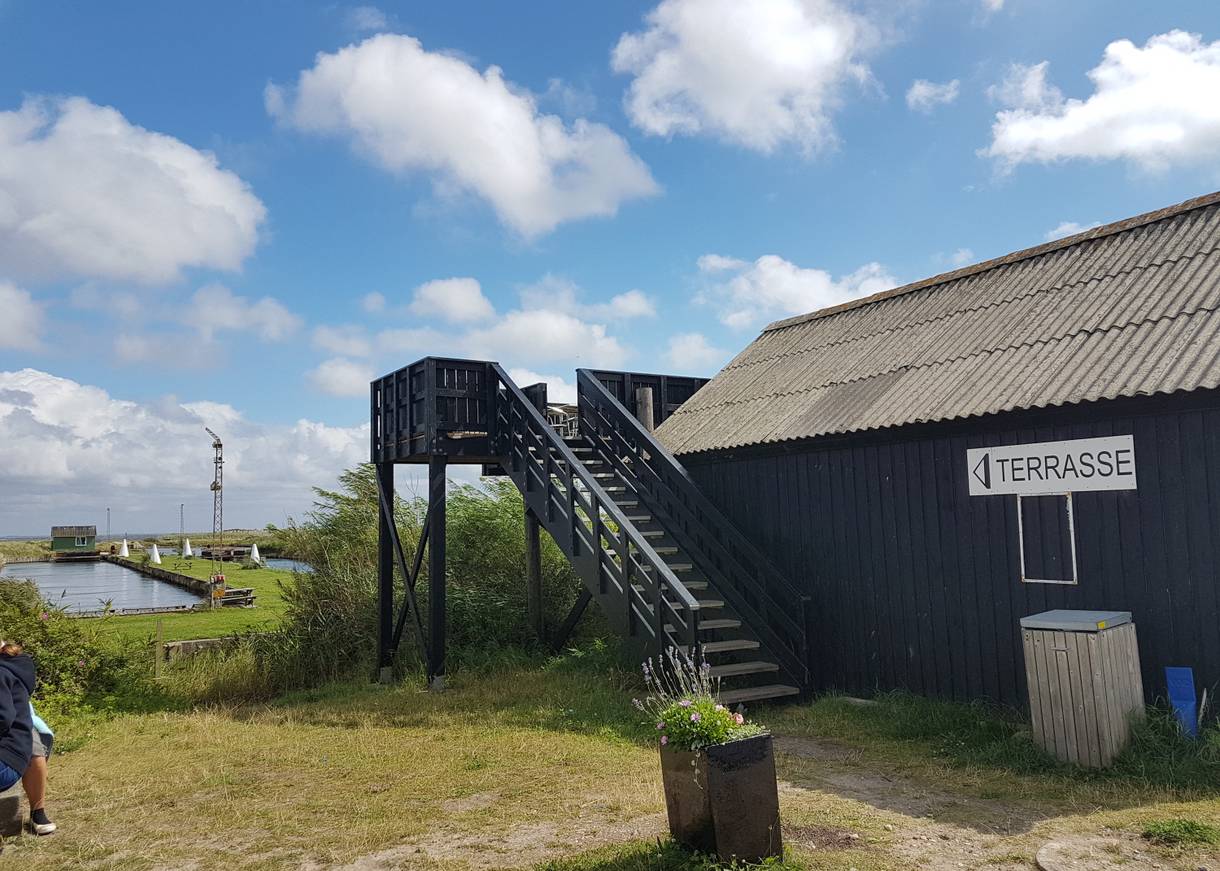 Holzterrasse als Anbau an einem schwarzen Schuppen