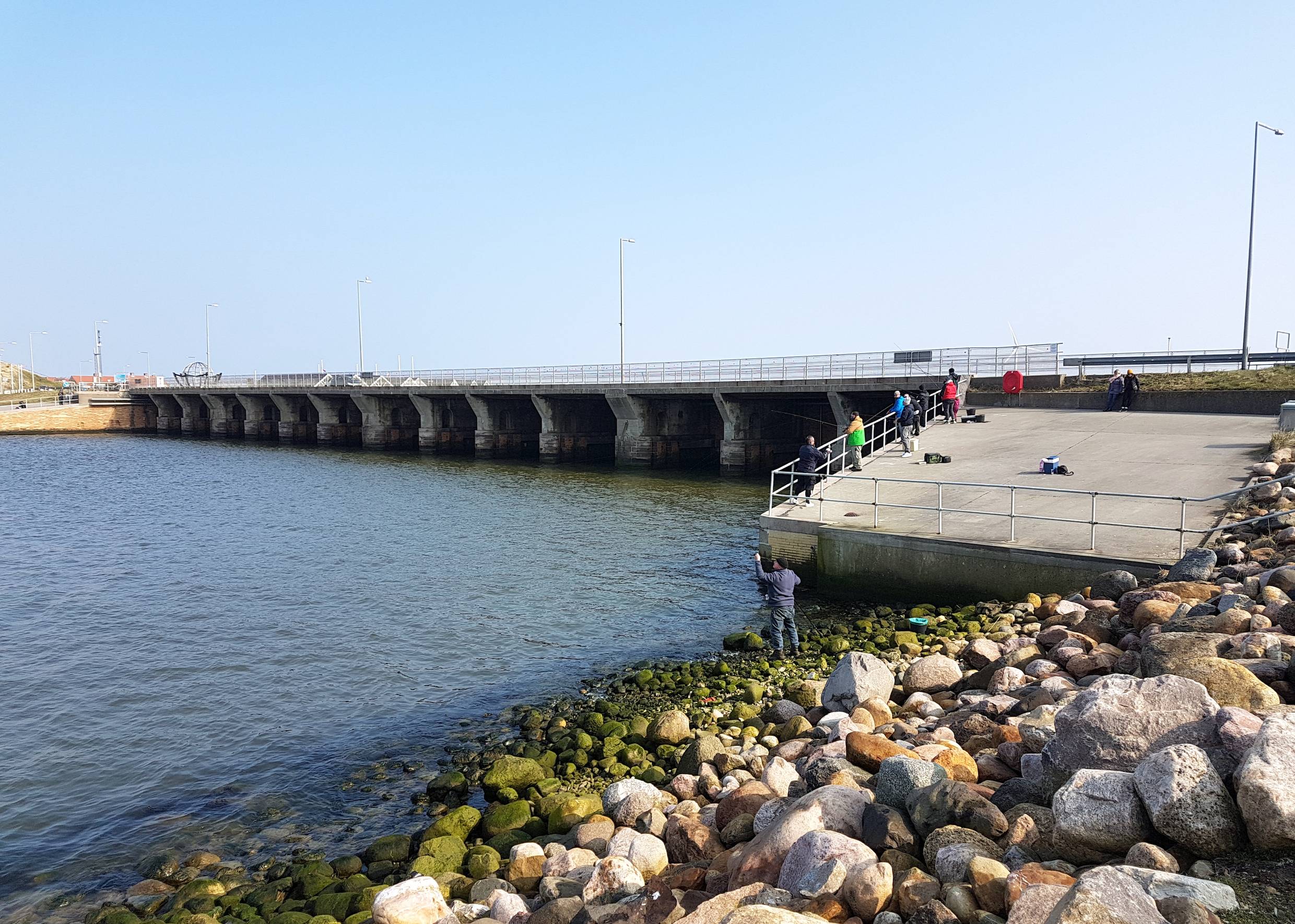 Blick auf die Schleuse, davor Angler an der Mole