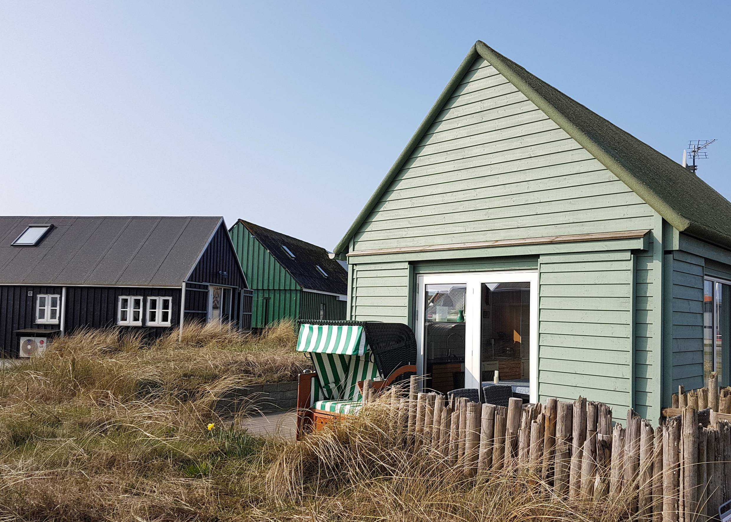 Kleines, hellgrünes Sommerhaus mit Strandkorb vor der Tür
