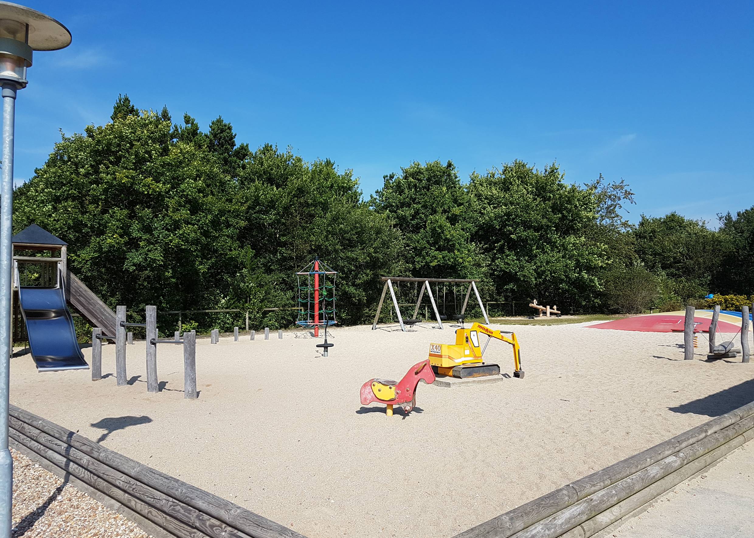 Spielplatz mit Sand, Hüpfkissen und allerlei Spielgeräten