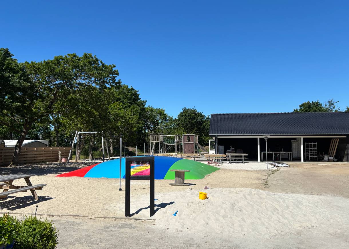Spielplatz mit Sand, Hüpfkissen und allerlei Spielgeräten