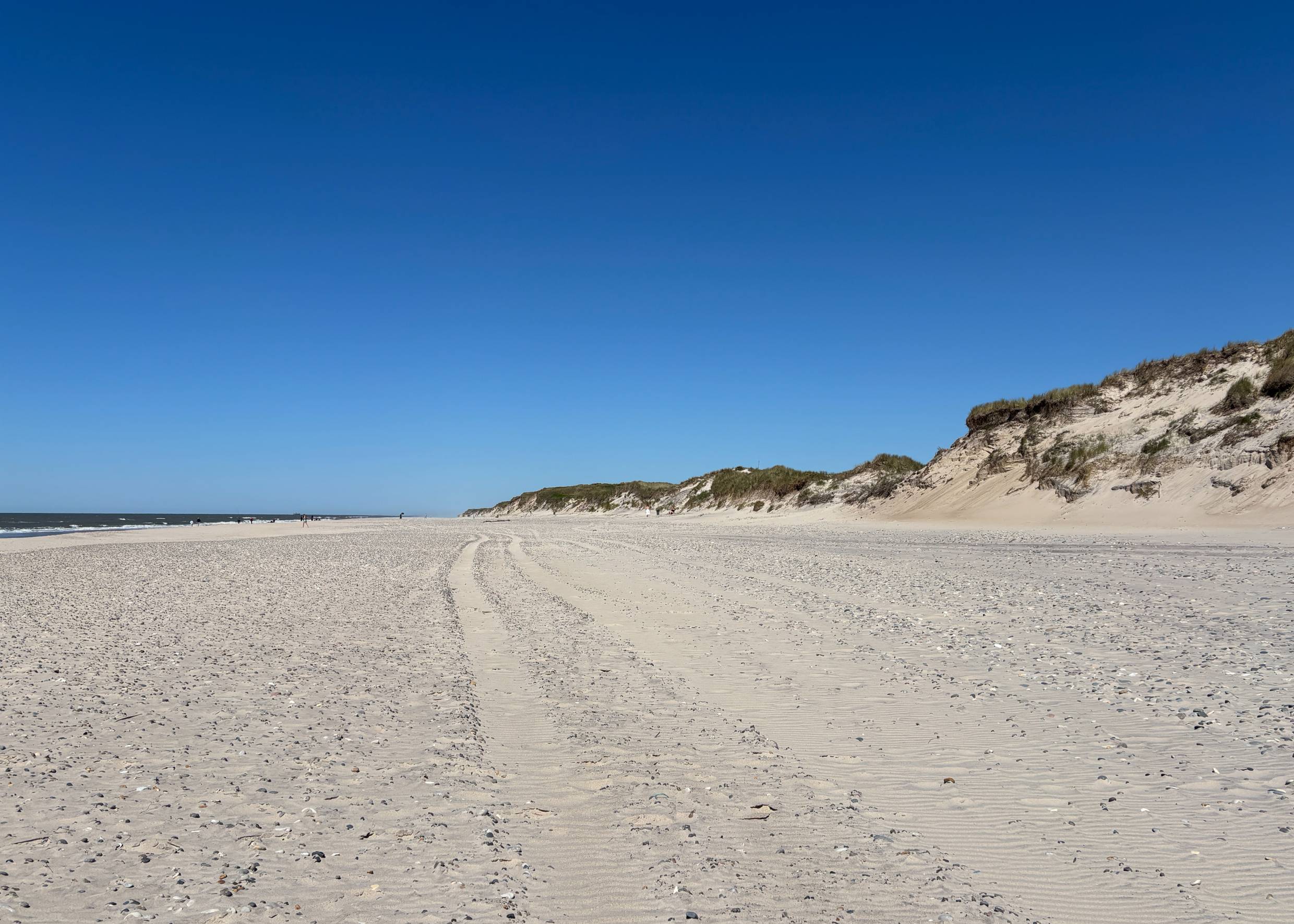 Ein großer, weißer Sandstrand unter blauem Himmel
